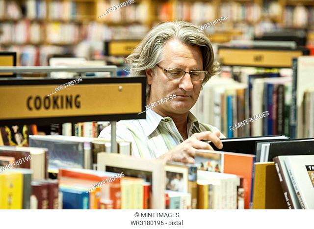 Caucasian male browsing through books in a large bookstore