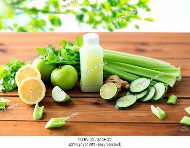 healthy eating, food, dieting and vegetarian concept - bottle with green juice, fruits and vegetables on wooden table over green natural background