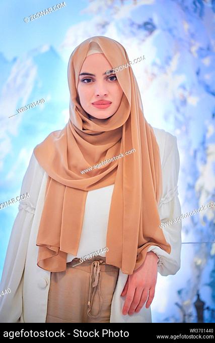 portrait of beautiful muslim woman in fashionable dress with hijab isolated on modern winter mountains background representing modern islam fashion and ramadan...