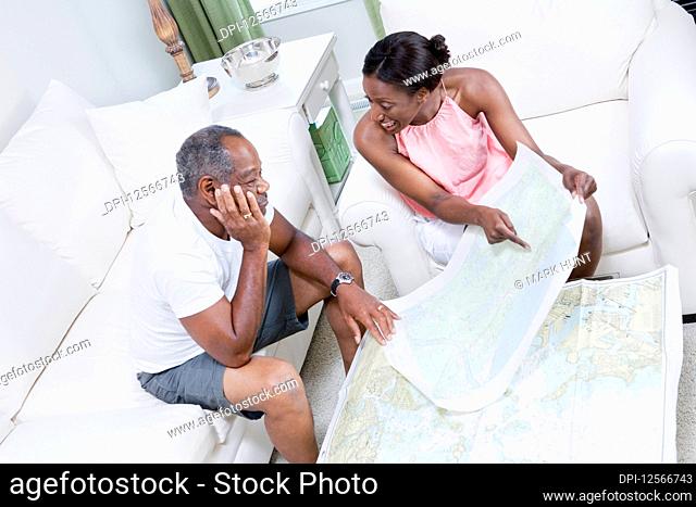 High angle view of a middle-aged couple sitting on a couch and studying a map of sailboat racing