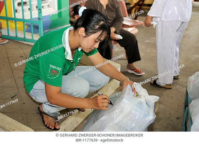 Sales clerk labelling a pack of fish sauce Nuoc Mam, Phu Quoc, Vietnam, Asia