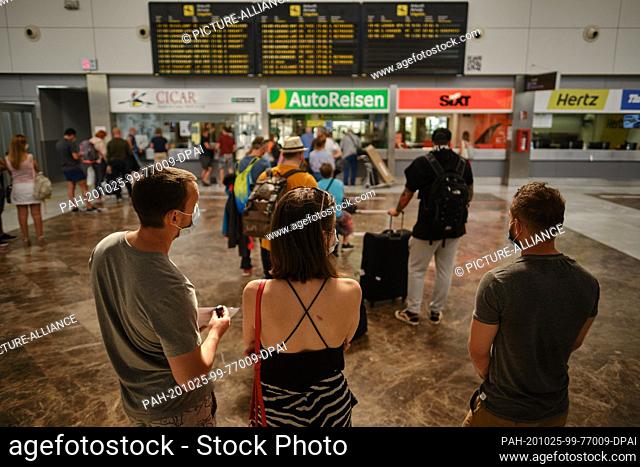 25 October 2020, Spain, Teneriffa: A young tourist couple is standing in front of a display board at Tenerife South Airport
