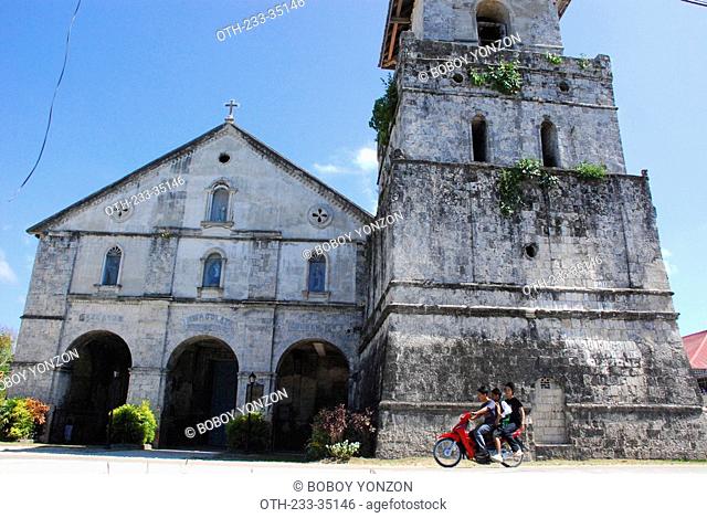 Family on a motorcycle passing by the church, Bohol, Philippines