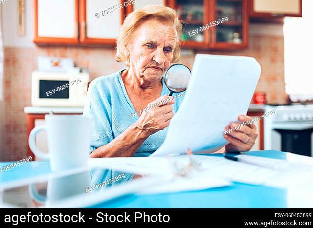 Elderly woman looking at her utility bills and paperwork