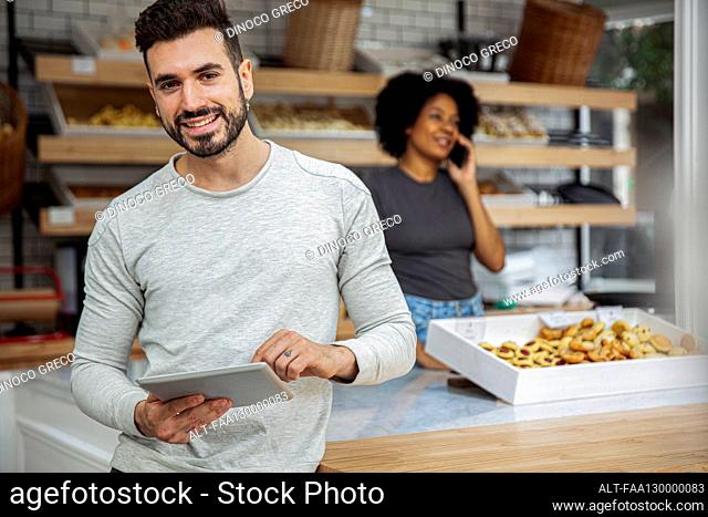 Bakery owner holding digital tablet in bakery
