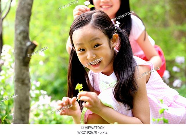 Two girls picking flower in field