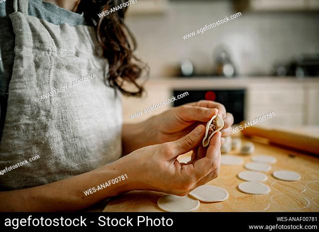 Woman preparing dumplings in kitchen at home