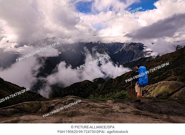 02 May 2019, Peru, Phuyupatamarka: A tourist stands on the viewpoint Phuyupatamarka and photographs the clouds in the Andes