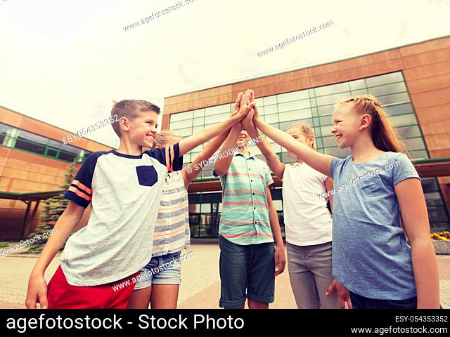 group of children making high five at school yard