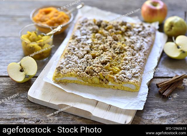 Vegan pumpkin and quark yeast dough strudel with apple and pear compote and oat and date crumbles on a wooden board