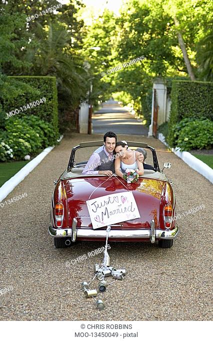 Portrait of newlyweds in vintage convertible