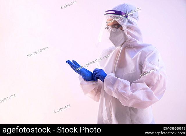 A health worker in PPE kit wearing gloves