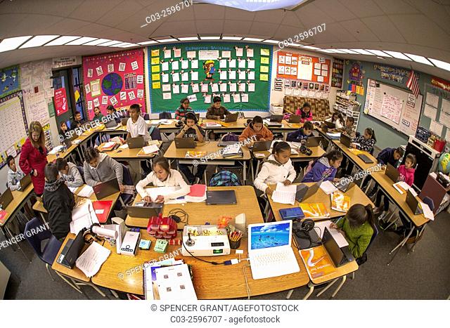 Hispanic third grade students enter information in their Google Chromebook laptop computers in a San Clemente, CA, elementary school classroom