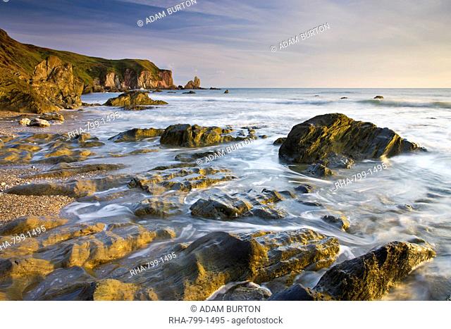 Late evening sunlight glows on the weathered rock ledges at Bantham in South Devon, England, United Kingdom, Europe