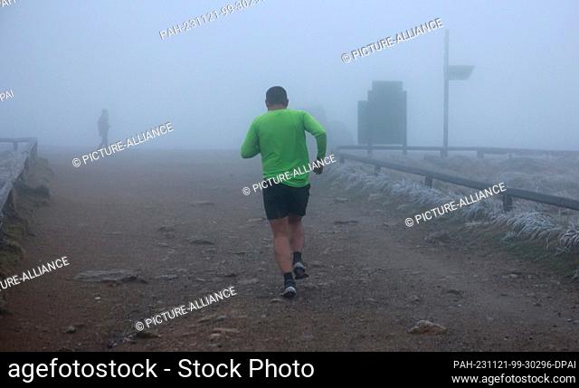 21 November 2023, Saxony-Anhalt, Schierke: Wearing shorts, a Brocken hiker is out and about on the Harz summit in frosty temperatures