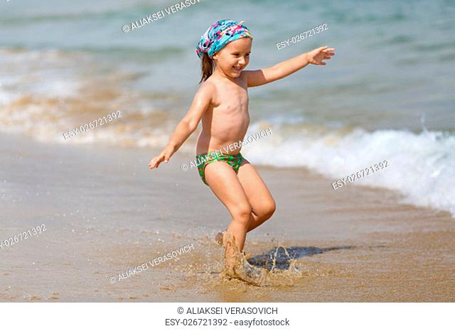 Laughing child running on the beach on a background of a sea wave. Shallow depth of field. Focus on model