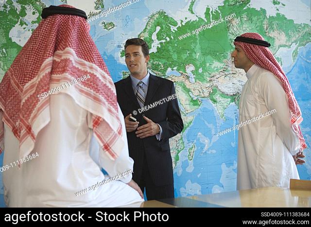 Middle Eastern businessman talking to men in traditional clothing