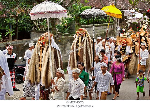 A BARONG COSTUME and LION MASKS used in traditional LEGONG dancing are carried during a HINDU PROCESSION for a temple anniversary - UBUD, BALI - 03/12/2010