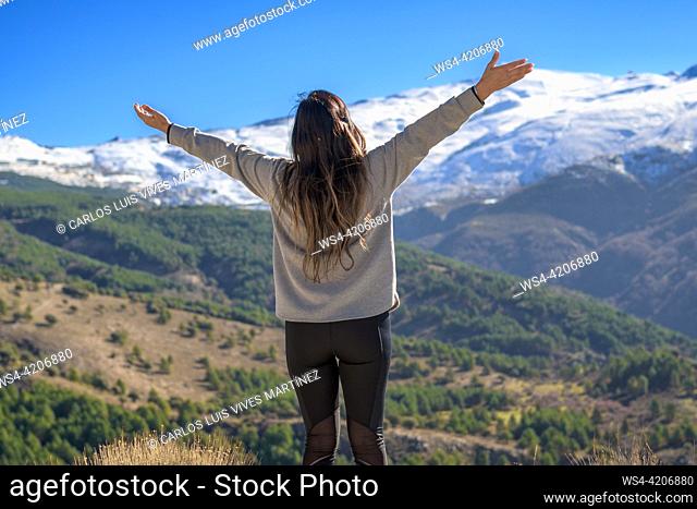 Latina woman opening her arms, enjoying the freedom. she has her back,