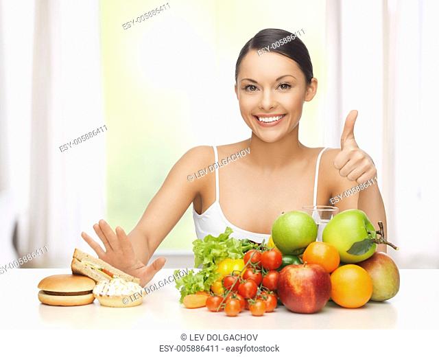 healthy and junk food concept - woman with fruits rejecting hamburger and cake