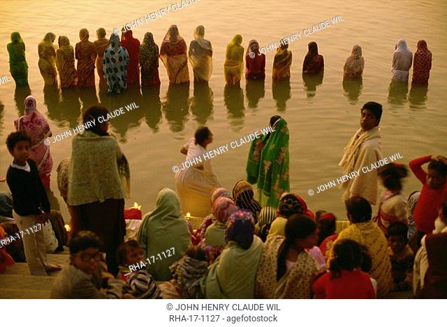 Hundreds of women gather in rows along river front, defying the cold, to welcome the rising sun god, Surya, Sun Worship Festival, Varanasi, Uttar Pradesh state
