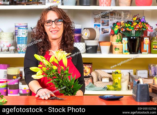 Smiling mature woman florist making a bouquet of flowers at flower shop