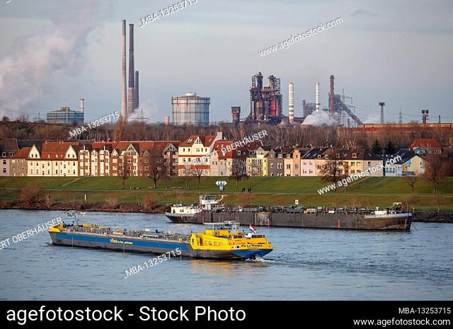 Duisburg, North Rhine-Westphalia, Germany - Urban landscape in the Ruhr area with a cargo ship on the Rhine in front of residential buildings in the Laar...