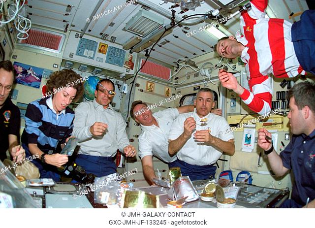 The Expedition Four and STS-110 crewmembers share a meal in the Zvezda Service Module on the International Space Station (ISS)