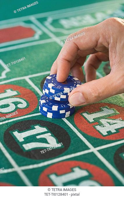 Man placing gambling chips on roulette table