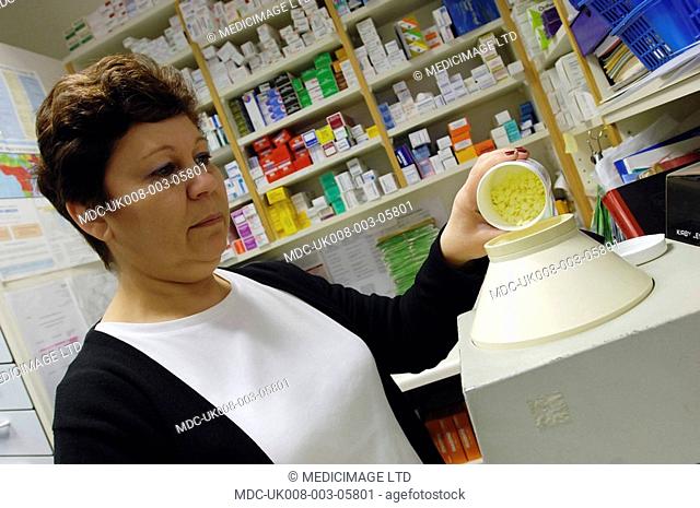 A pharmacist uses a pill counting machine to make sure that she gives the right amount of medication to the customers