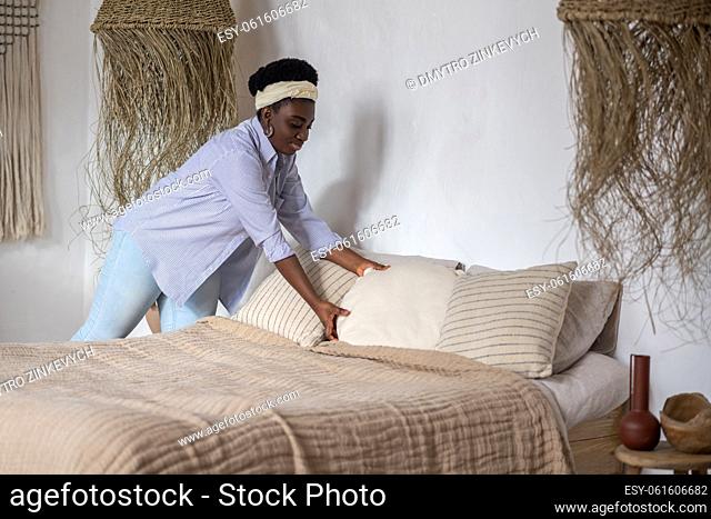 Making bed. Dark-haired woman making bed in the bedroom