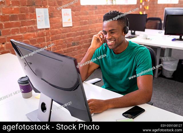 African american businessman having video call sitting in front of computer using headphones