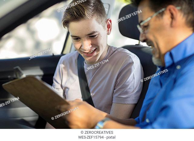Learner driver with instructor in car looking at test script