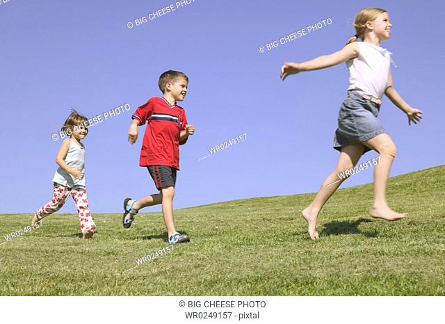 Three children running along a hillside
