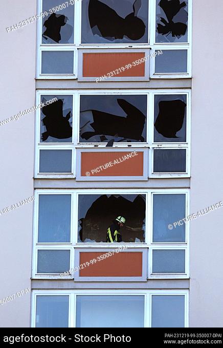 19 December 2023, Bavaria, Mindelheim: A firefighter walks behind broken windows in the stairwell of a nine-storey apartment building