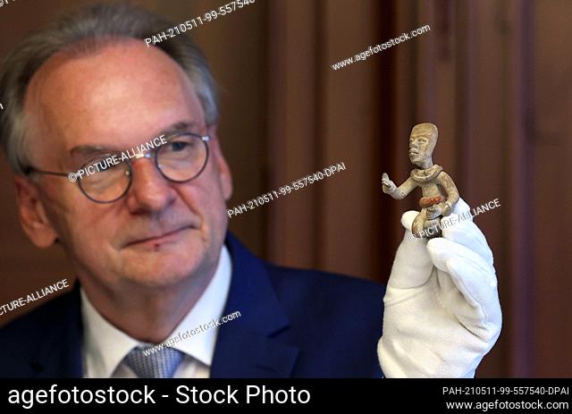 11 May 2021, Saxony-Anhalt, Magdeburg: Reiner Haseloff (CDU), Minister President of Saxony-Anhalt, presents a clay figure of a kneeling man from the Mexican...