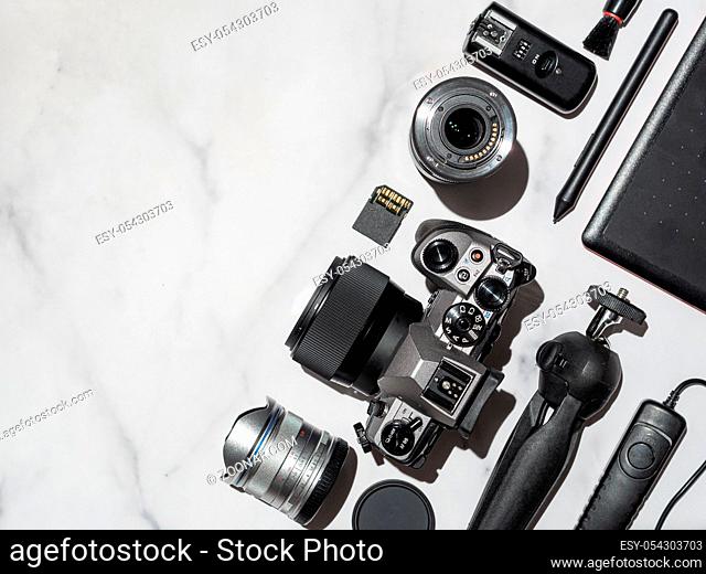 Photographer workplace with dslr camera, lens, pen tablet and camera accessories on white marble background. Camera, photography, visual content concept