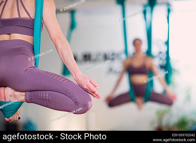 Woman doing aerial yoga in studio. Female practicing air yoga in hammock