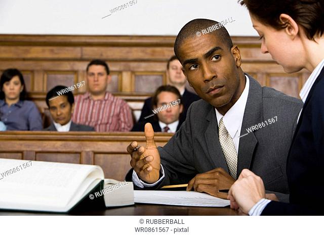 A male lawyer looking at another lawyer in a courtroom