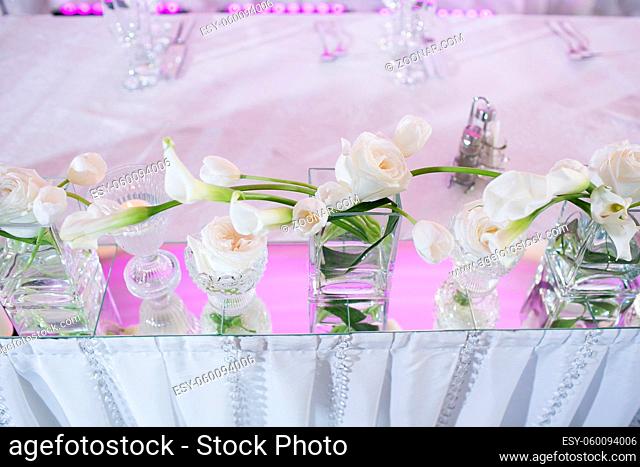 Beautiful restaurant interior table decoration for wedding. Flower Wedding Table Decoration. White calla lilies and tulips in vases. Candles