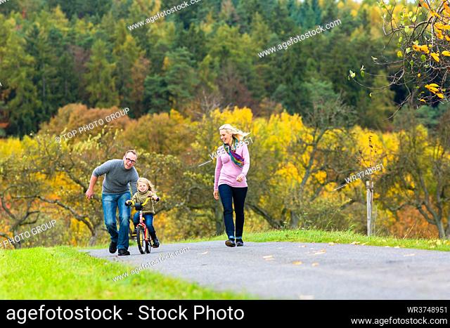 Girl learning bicycling in fall or autumn park