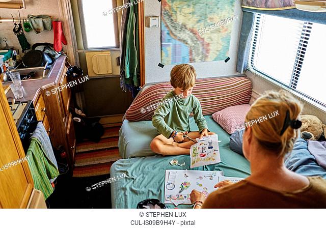Mother and son cutting out pictures in campervan, Chuquisaca, Bolivia, South America