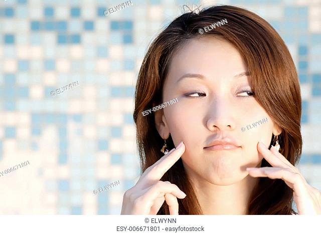 Here is a beautiful Asian lady in front of mosaic with funny face
