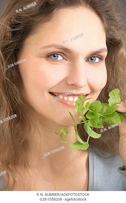 portrait of a young woman holding and smelling a sprig of mint