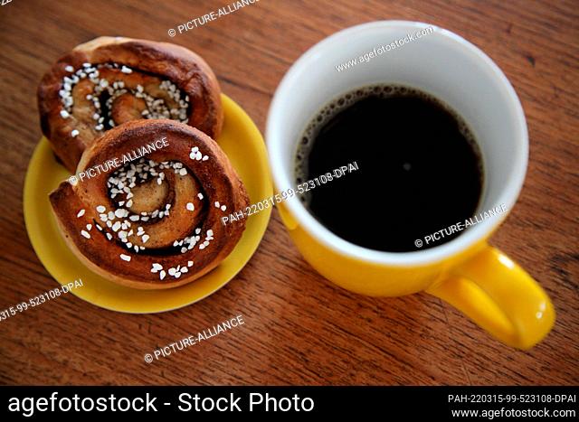 ILLUSTRATION - 14 March 2022, Denmark, Kopenhagen: Two cinnamon buns lie next to a coffee mug. A secret means of Swedish happiness is found in the daily coffee...