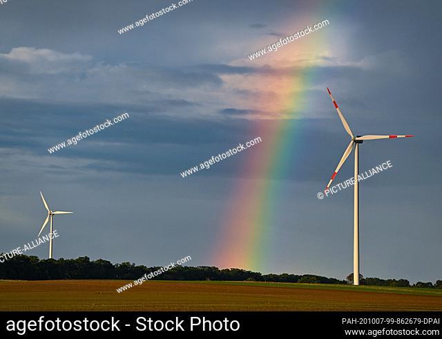 07 October 2020, Brandenburg, Petersdorf: A rainbow spans the landscape with two wind turbines in the ""Odervorland"" wind farm in the Oder-Spree district