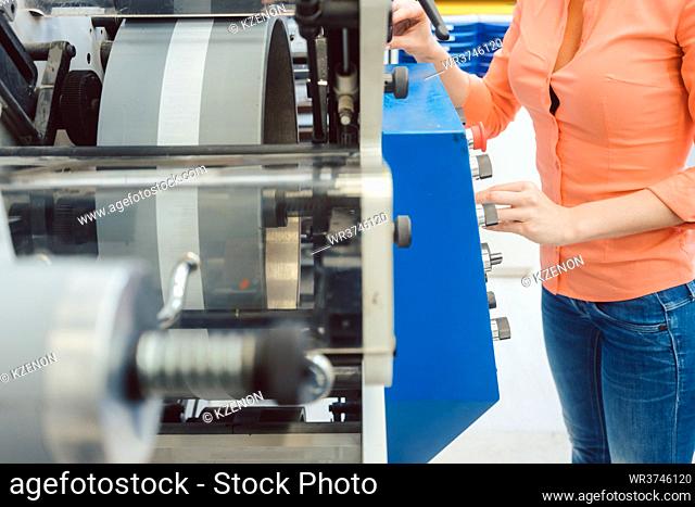 Woman pressing start button on label printing machine in print shop