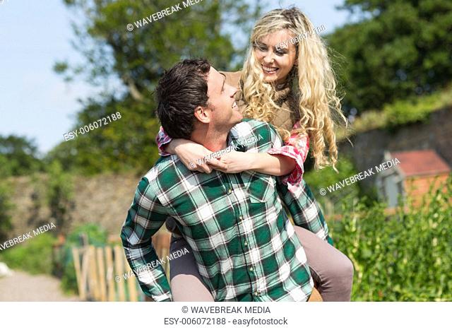 Handsome man giving his girlfriend a piggyback ride