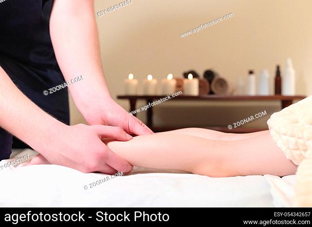 Close-up of male chiropractor hands massaging calves of a small patient. A little boy at the reception of the procedure of massage in the office of physical...