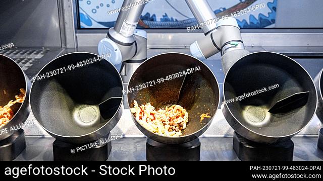 PRODUCTION - 20 July 2023, Schleswig-Holstein, Grömitz: A robot prepares dishes in induction trays in the restaurant of a hotel. to